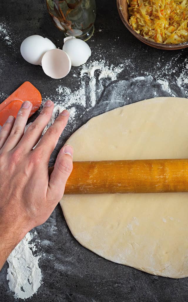 A Chef Rolling Out a Pizza Base